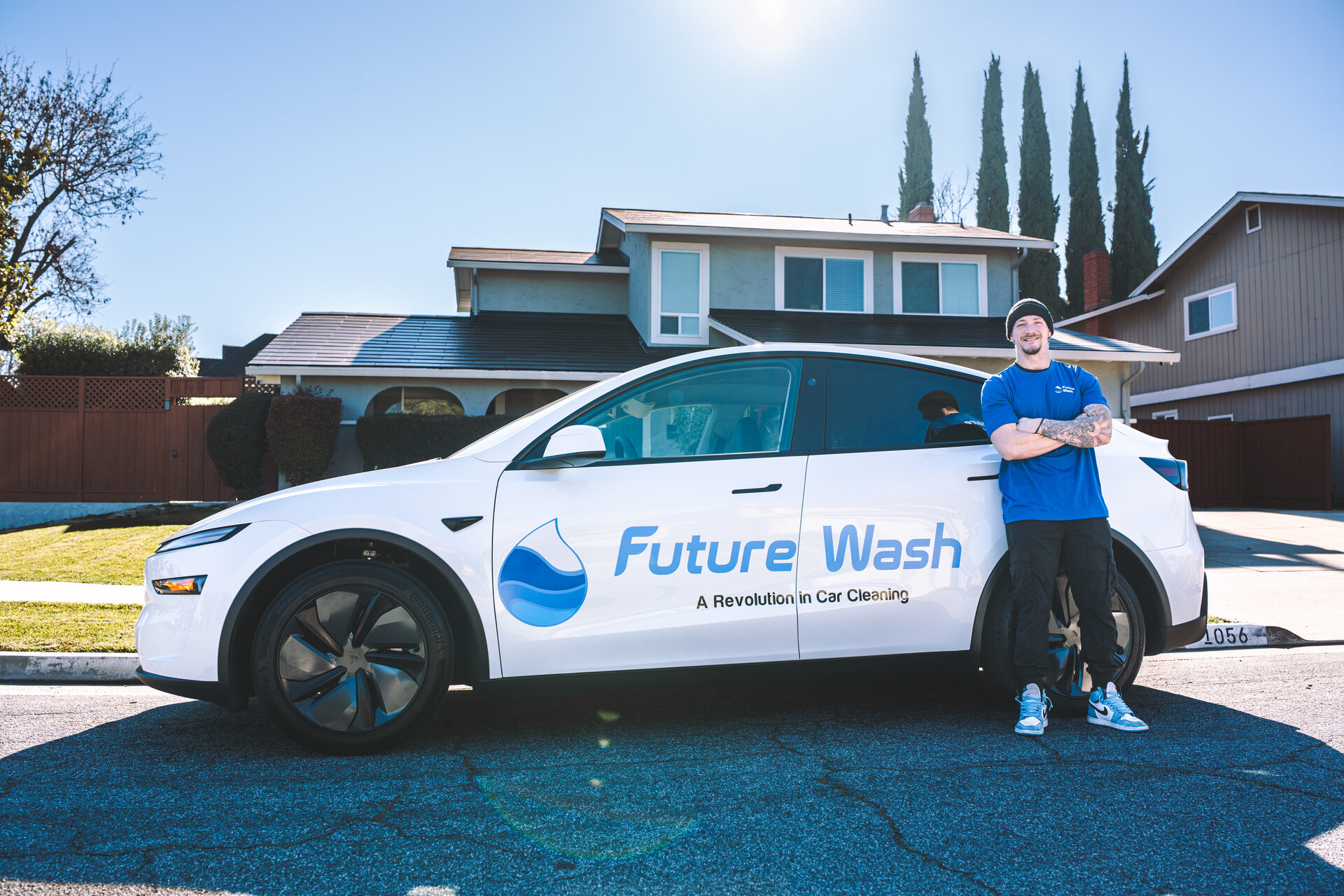 Future Wash technician standing beside a branded Tesla Model Y outside a Bay Area home