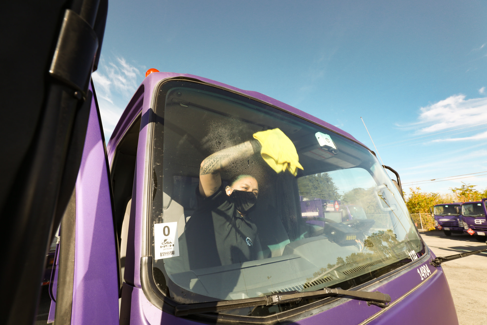Future Wash technician cleaning the windshield of a purple branded fleet truck