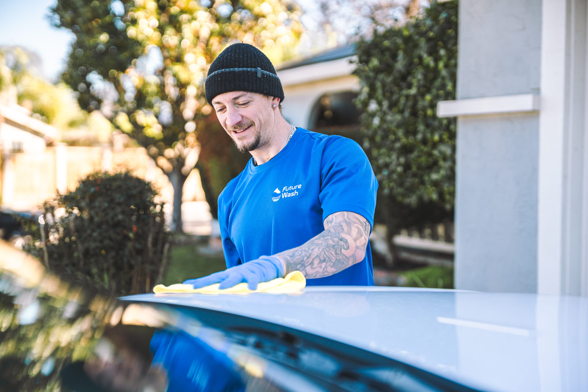Future Wash technician polishing the roof of a white car with a yellow microfiber cloth